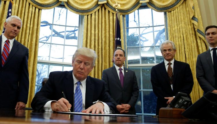 Le président américain Donald Trump, regardé par le vice-président Mike Pence, signe un décret qui met un gel de l'embauche des travailleurs fédéraux non militaires dans le bureau ovale de la Maison Blanche à Washington 23 janvier 2017