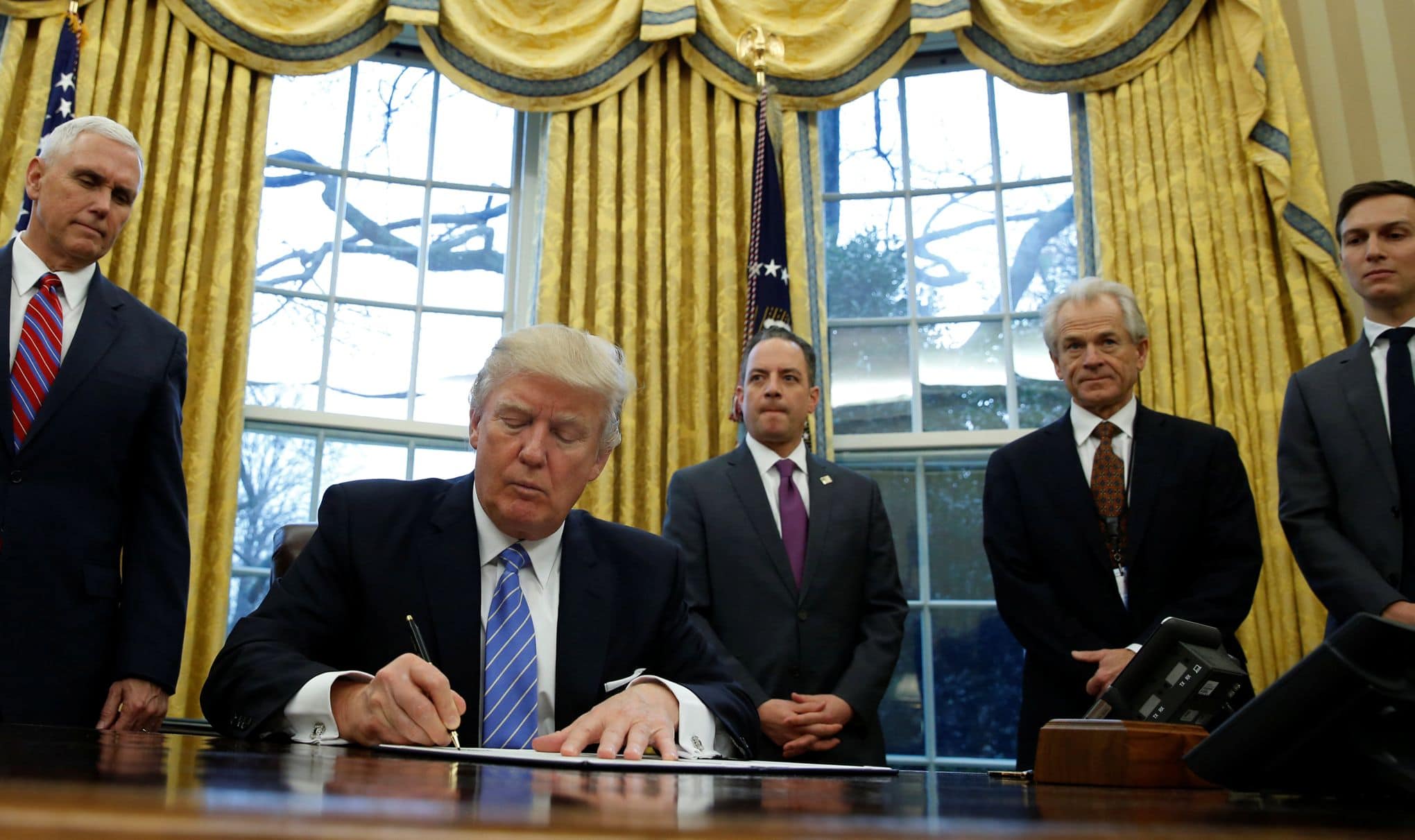 Le président américain Donald Trump, regardé par le vice-président Mike Pence, signe un décret qui met un gel de l'embauche des travailleurs fédéraux non militaires dans le bureau ovale de la Maison Blanche à Washington 23 janvier 2017